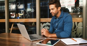 Man sitting at desk with laptop and iPad