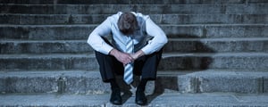 Man on stairs with head hanging low